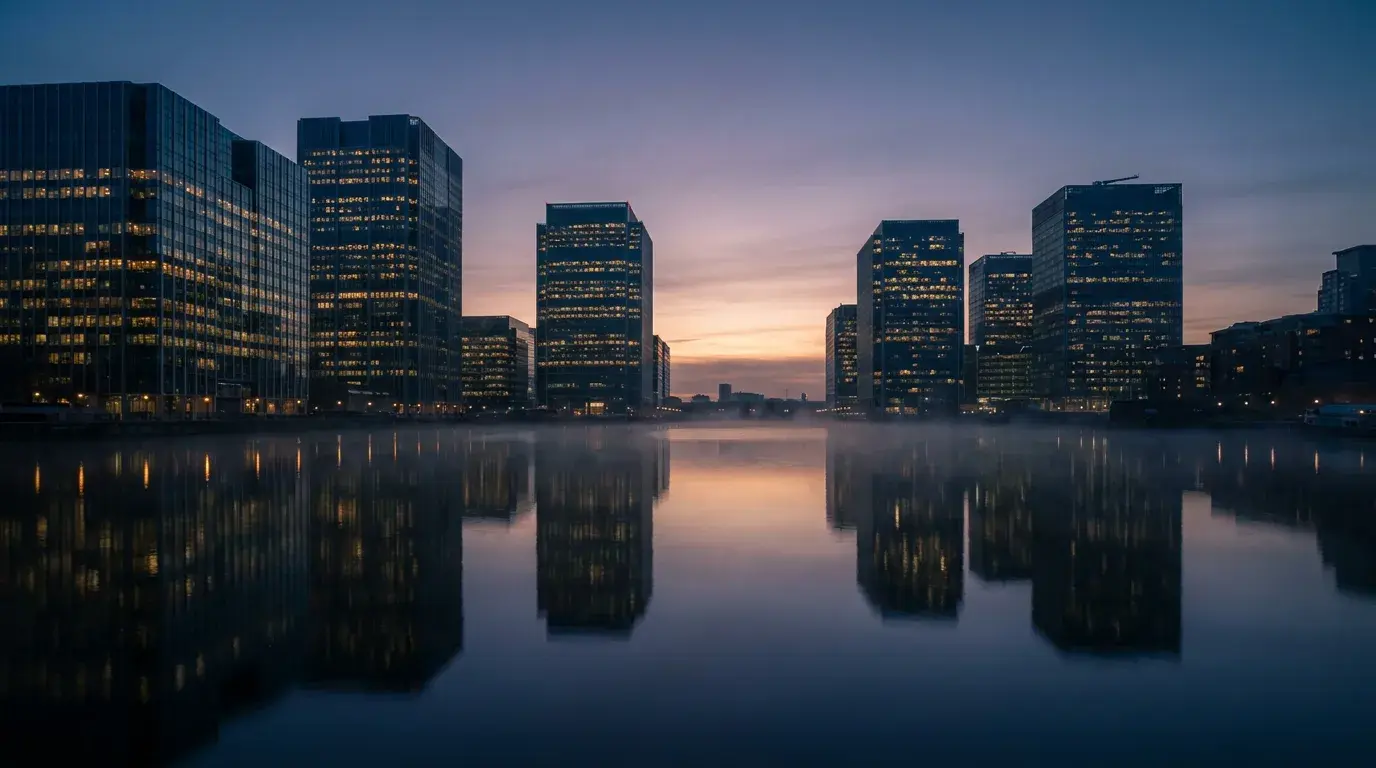 Cinematic stylized financial-district skyline of glass towers at dusk bathed in warm golden light against a deep blue twilight sky
